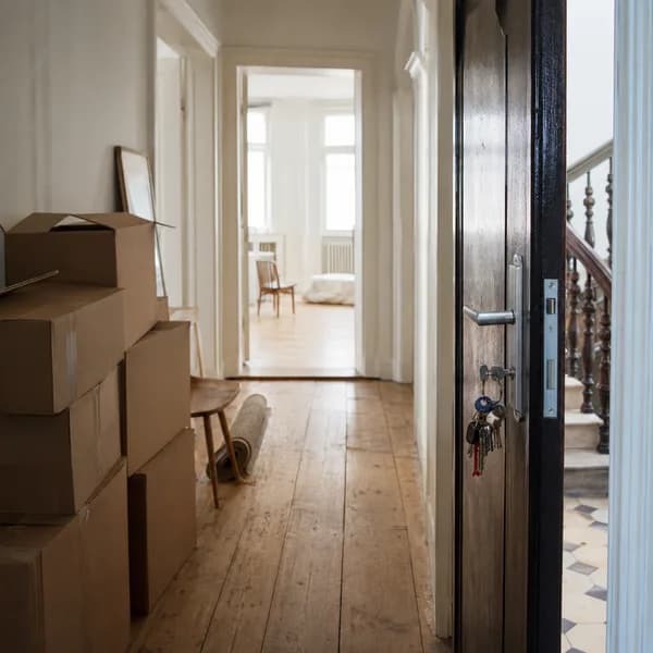 Umzugskartons im Flur einer Altbauwohnung mit Schlüsselbund in der geöffneten Wohnungstür